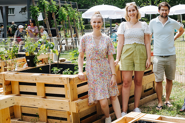 Drei Personen im Nachbarschaftsgarten vor einem Hochbeet