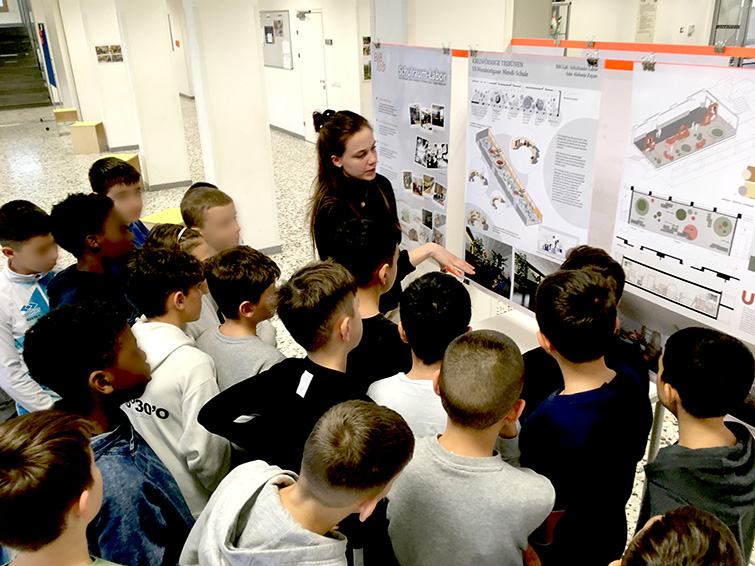 Gruppe an Schüler*innen hört gespannt der Präsentation zu